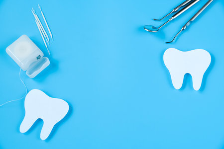 Happy International Dentist Day. Paper cut mockup of tooth and dental tool on blue background. Dental care concept. Greeting card for professional holiday. Copy space.の写真素材