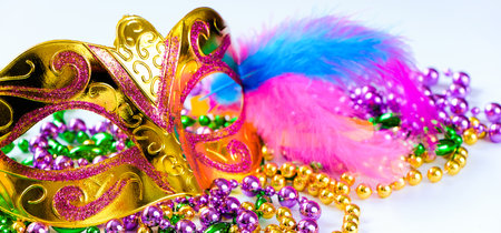 Golden carnival mask and colorful beads on white background. Closeup symbol of Mardi Gras or Fat Tuesday. Holiday decorations in gold, green and purple. Banner formatの写真素材
