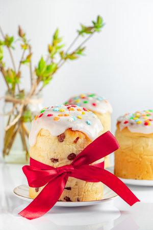 Delicious Easter cakes decorated with ribbon and flowers on white background. Festive food.
