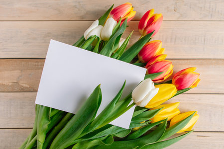 Colorful tulips bouquet and greeting card on wooden background. Holiday gift. Spring symbol, place for text.の写真素材