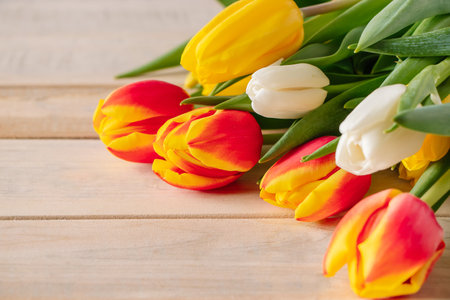 Fresh multicolored tulips on wooden background. Bouquet of spring flowers. Holiday concept.の写真素材