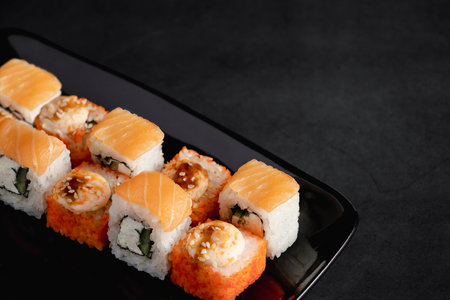 Set of Philadelphia sushi rolls on black plate. Serving Japanese food in restaurant. Popular Asian dish of rice and salmon. Uramaki rolls. Copy space.の写真素材