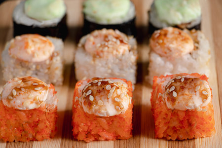 Set of sushi rolls on bamboo serving tray. Uramaki and futomaki roll close-up. Serving Japanese food. Popular Asian dish of rice and seafood on black background.の写真素材