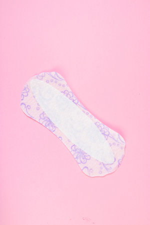 Sanitary pad on pink background. Daily feminine hygiene product. Menstruation and womens health concept. Vertical photo.の写真素材
