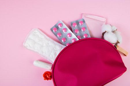 Pink cosmetic bag and set of feminine hygiene products for menstruation. Sanitary pads, tampons, pills. Womens health concept. Copy space.の写真素材
