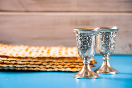 Happy passover. Metal goblet and traditional matzah on blue background. Symbols of Jewish holiday.