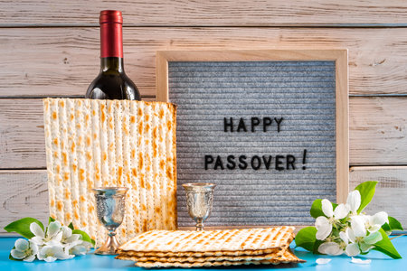 Celebrating spring holiday Passover. Bottle of wine and traditional Jewish matzo bread on blue...