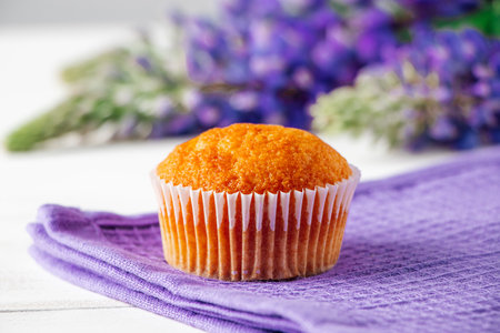 Freshly baked muffin and purple lupins on white wooden background. Homemade baking, preparing sweet dessert. Summer recipe.の写真素材