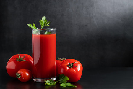 Fresh tomato juice in a glass on dark background. Vegetable diet drink with parsley.の写真素材