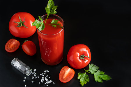 Fresh tomato juice in a glass on dark background. Vegetable diet drink with parsley.の写真素材