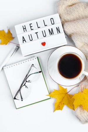 Autumn morning concept. Cup of hot espresso coffee and fallen leaves on a white background. Warm beverage for cold weather and knitted sweater.の写真素材