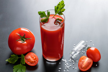 Fresh tomato juice in a glass on dark background. Vegetable diet drink with parsley.の写真素材
