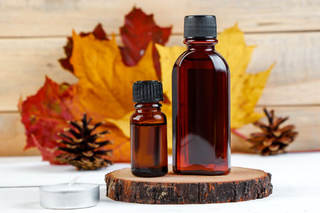 Autumn skin care concept. Bottle of pine essential oil on a white wooden background. Aromatherapy and eco-friendly cosmetics. Copy space.の写真素材