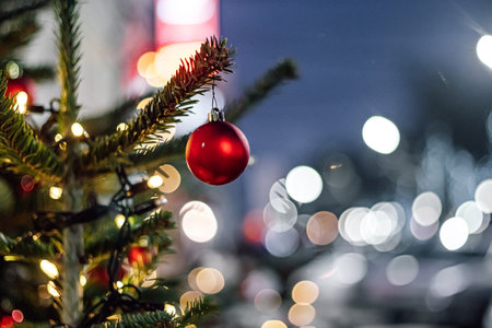 Red Christmas balls and garlands on branch. Christmas tree with decor. Holiday season, street decorations.の写真素材