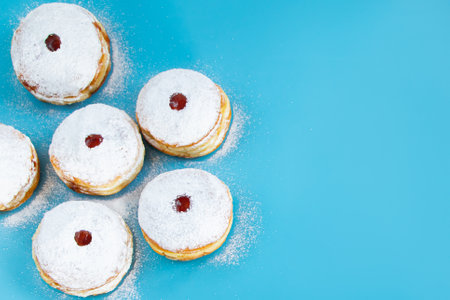 Symbols of Jewish religious holiday Hanukkah. Traditional dessert donuts sufganiyot on blue background. Copy space.の写真素材