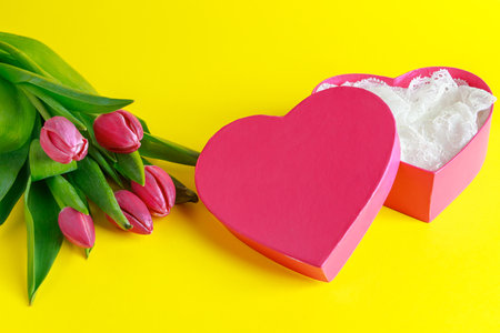 Tulips and pink heart shape box on yellow background. Valentines day greeting card. Place for text.の写真素材