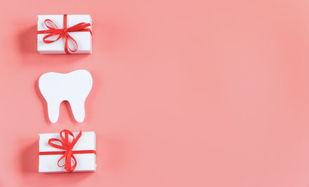 Happy dentist day. Paper cut mockup of tooth and gift boxes on pink background. Dental care concept. Greeting card. Copy space.の写真素材