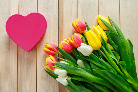 Tulips and heart on wooden background. Valentine's day greeting card concept.の写真素材