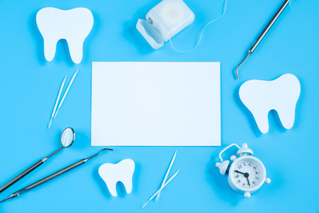 Happy International Dentist Day. Paper cut mockup of tooth and dental tool on blue background. Dental care concept. Greeting card for professional holiday. Copy space.の写真素材