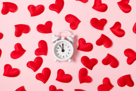 Time for love. Alarm clock and red hearts on pink background. Valentine's day concept, banner format.の写真素材