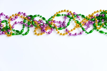 Mardi Gras background. Multicolored beads on white background. Fat Tuesday symbol. Festive decorations in gold, green and purple colors for traditional holiday. Copy space.の写真素材