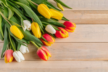 Fresh multicolored tulips on wooden background. Bouquet of spring flowers. Holiday concept.の写真素材