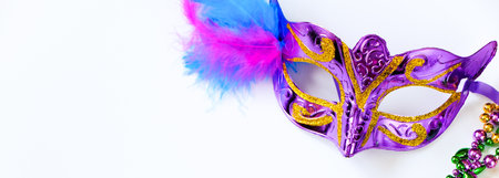 Carnival mask with feathers and colorful beads on white background. Mardi Gras or Fat Tuesday symbol. Festive decorations for traditional holiday. Copy space, banner format.の写真素材
