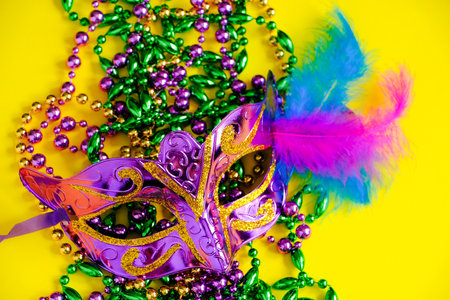Carnival mask and beads on yellow background. Mardi Gras concept. Fat Tuesday symbol. Holiday decorations close up.の写真素材