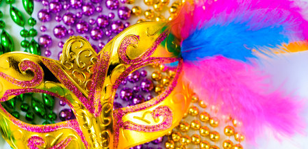 Golden carnival mask and colorful beads close-up. Mardi Gras or Fat Tuesday symbol. Concept of traditional festival. Holiday decorations in gold, green and purple.の写真素材