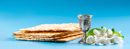 Happy passover. Metal goblet and traditional matzah on blue background. Symbols of Jewish holiday. Banner format.の写真素材