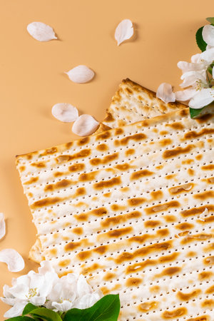 Traditional Jewish holiday Passover. Spring flowers and matzo bread on beige background. Copy space. Festive flatlay. Vertical photo.の写真素材