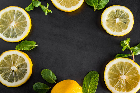 Fresh juicy lemon slices on black background. Cocktail ingredient - mint leaves and lemon. Food background. Copy space.の写真素材