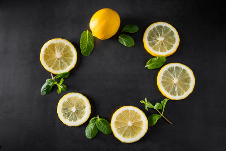 Fresh juicy lemon slices on black background. Cocktail ingredient - mint leaves and lemon. Food background.の写真素材