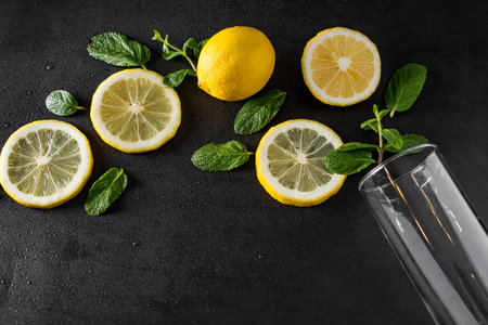 Fresh juicy lemon and mint leaves on black background. Ingredients for summer cocktail. Food background. Advertising concept of refreshing drink. Copy space.の写真素材