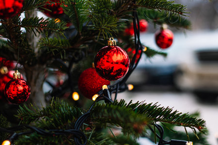 Red Christmas balls and garlands on branch. Christmas tree with decor. Holiday season, street decorations.の写真素材