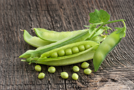 Pods of green peas on a wooden surface, close-upの写真素材