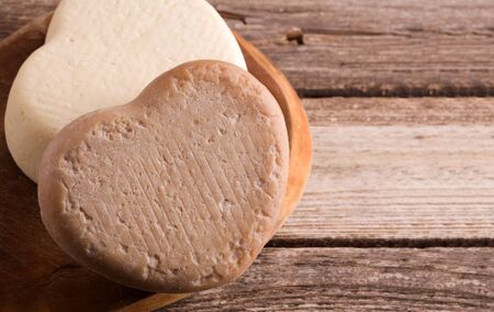 Cheese in the shape of a heart on a wooden table. Place for text.の写真素材