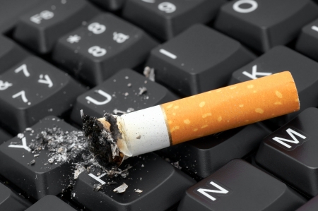Cigarette and ash on a computer keyboard の写真素材