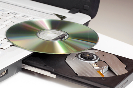 CD DVD disc lying on a laptop with a protruding drive 