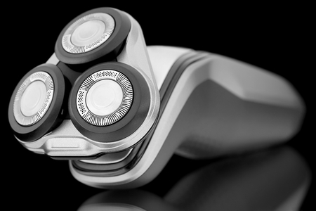 Electric shaver lying on a shiny surface.の写真素材