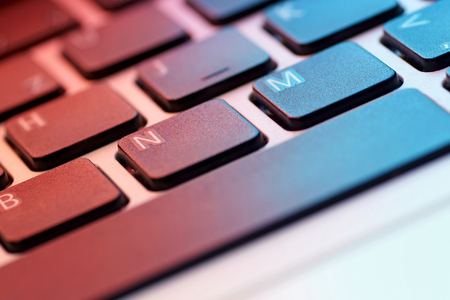 Close-up of a laptop keyboard lit by monitor.
