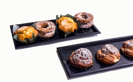 Chocolate donuts on a black plate isolated on white background.