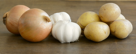 Long close up of fresh onions, garlic, and potatoesの写真素材