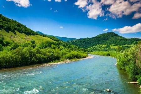 wild river flowing between green mountains on a clear summer dayの写真素材