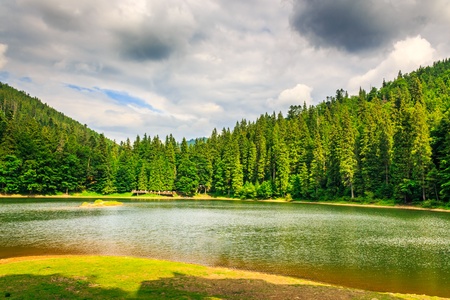 large mountain lake shore. among the pine trees in the mountains. evening before the stormの写真素材