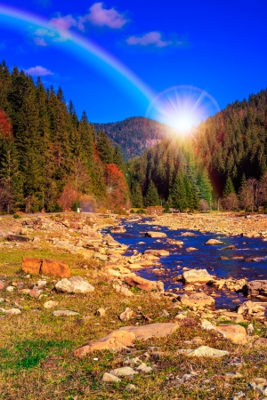 river flows by rocky shore near the autumn mountain forestの写真素材
