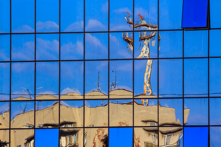 new window with a mirror coating reflects near-standing building with tv antena