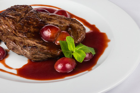 juicy grilled beef steak with plums in sauce with mint and summer tasteの写真素材