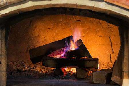 Real roaring wood fire and open brick Indoor fireplace system with logs and purple flameの写真素材