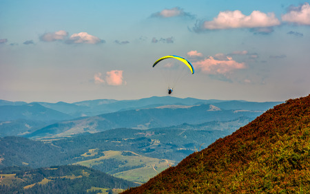 Skydiver flying in the clouds over the countryside valley at sunset. parachute extreme sportの写真素材